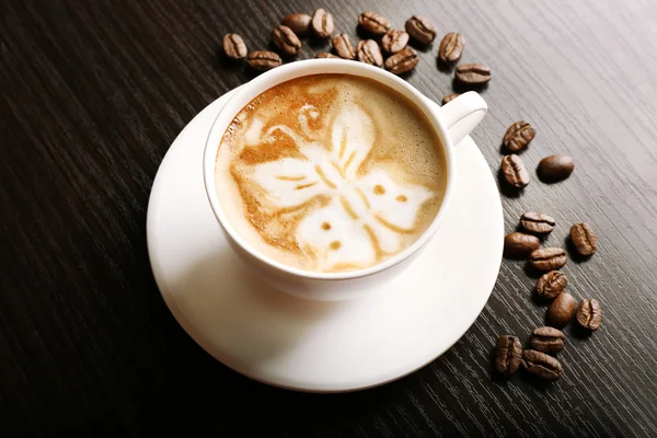 Tasse de café latte art avec des grains sur fond en bois — Photo