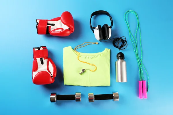 Sports equipment and T-shirt on color table, top view — Stock Photo, Image