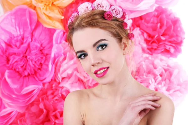 Portrait of young woman with flowers in hair on bright pink background — Stock Photo, Image