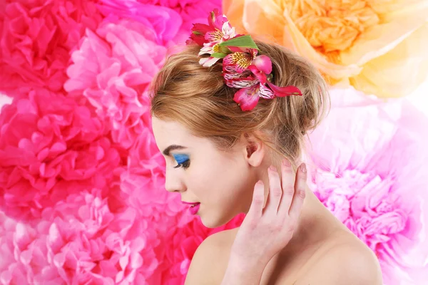 Retrato de mulher jovem com flores no cabelo em fundo rosa brilhante — Fotografia de Stock