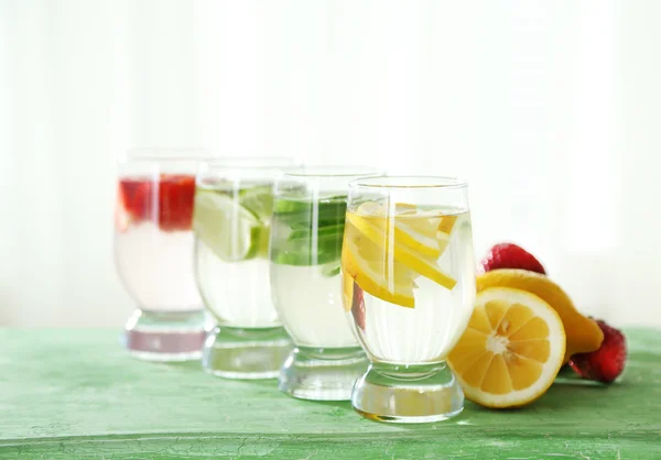 Okulary w różne domowe świeżość zdrowych wzbogacone w witaminy wody na drewnianym stole — Zdjęcie stockowe