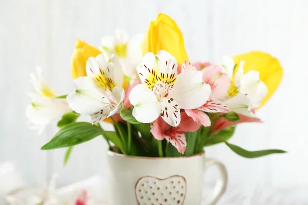 Beautiful flowers in cup, on wooden background — Stock Photo, Image