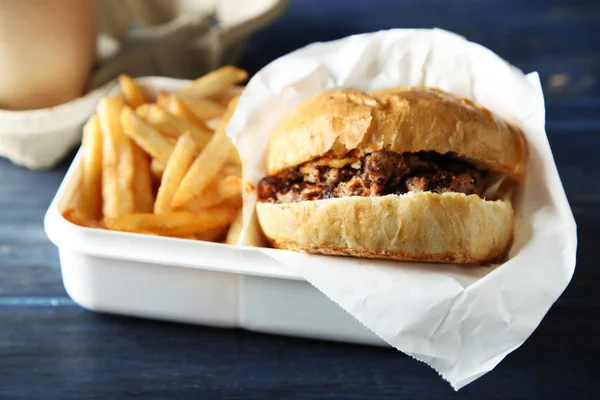 Вкусный бургер и картофель фри на фоне деревянного стола, крупным планом Нездоровое питание — стоковое фото