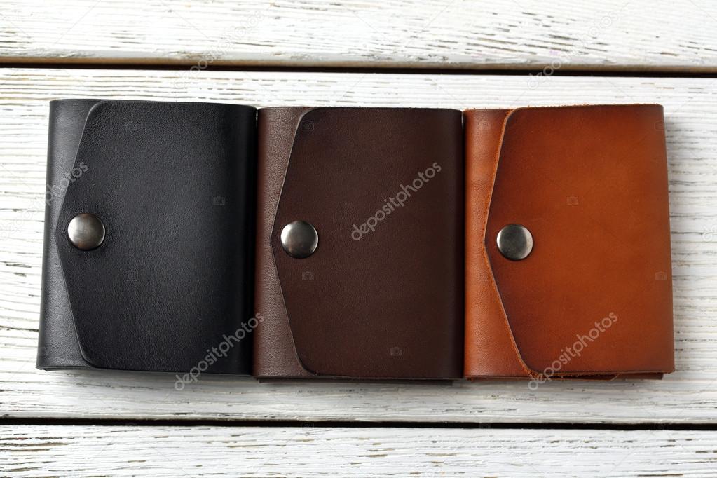 Three hand made leather man wallets on white wooden background