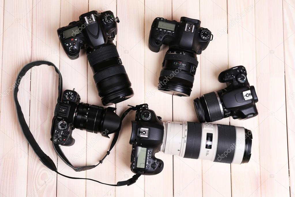 Modern cameras on wooden table, top view