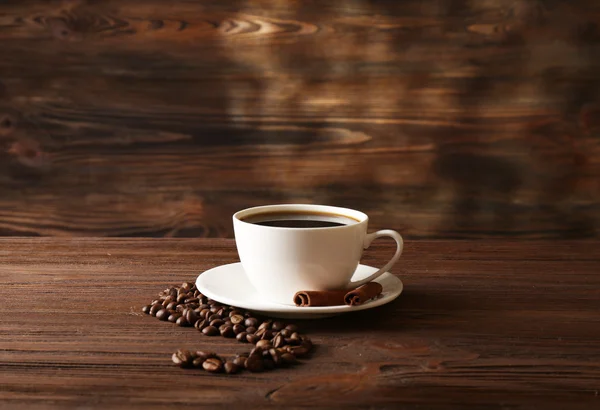 Xícara de café com grãos em fundo de madeira — Fotografia de Stock