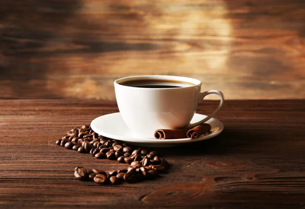 Cup of coffee with grains on wooden background — Stock Photo, Image