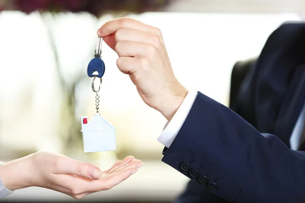 Ruka podnikatel dát klíče k ženské ruky na rozmazané pozadí — Stock fotografie