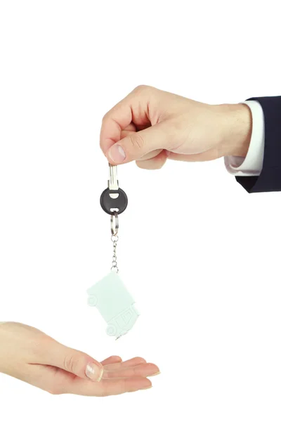 Mano masculina dando llave con baratija a mano femenina aislada en blanco — Foto de Stock
