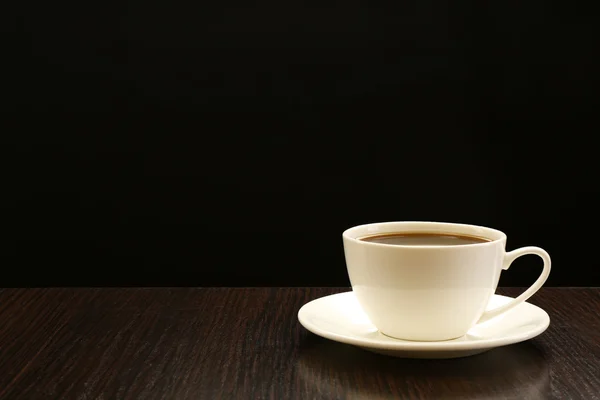 Cup of coffee on wooden table, on dark background — Stock Photo, Image