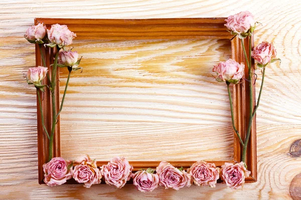 Photo frame with dried flowers on wooden background — Stock Photo, Image