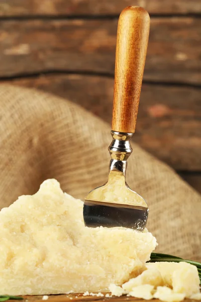 Cheese with blade on wooden table with sackcloth, closeup — Stock Photo, Image