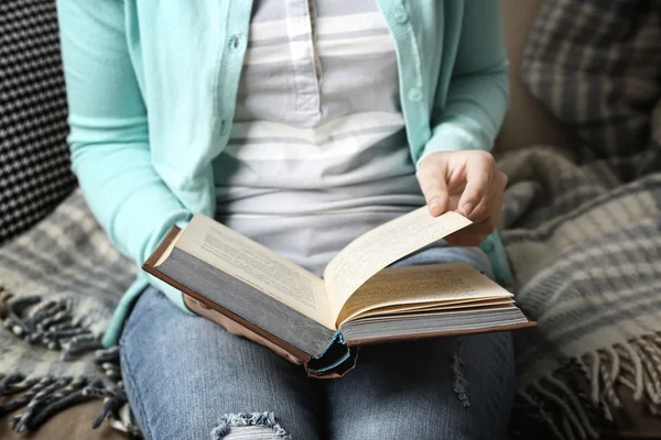 Joven leyendo libro, primer plano, en el fondo interior de casa — Foto de Stock