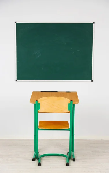 Quadro negro e mesa de madeira com cadeira na sala de aula — Fotografia de Stock