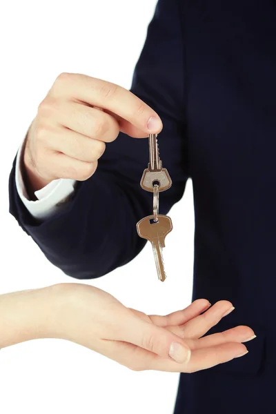 Male hand giving key with trinket to female hand isolated on white Royalty Free Stock Images