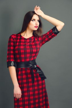 Koyu gri arka plan üzerinde kare elbiseli güzel genç kadın