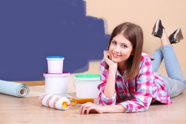 Güzel kız boyama duvar için ekipman ile yerde yatarken
