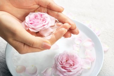 Female hands with bowl of aroma spa water on table, closeup clipart