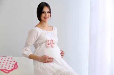 Beyaz duvar arka koltukta oturan bebek patik ile hamile kadın