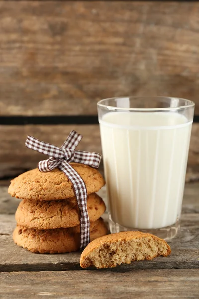 Biscoitos saborosos e copo de leite no fundo de madeira rústica — Fotografia de Stock