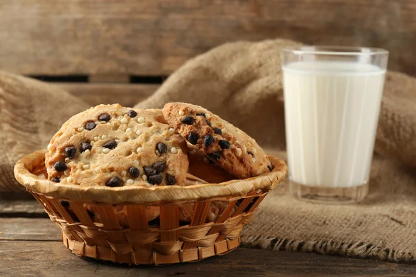 Sabrosas galletas y vaso de leche sobre fondo rústico de madera — Foto de Stock