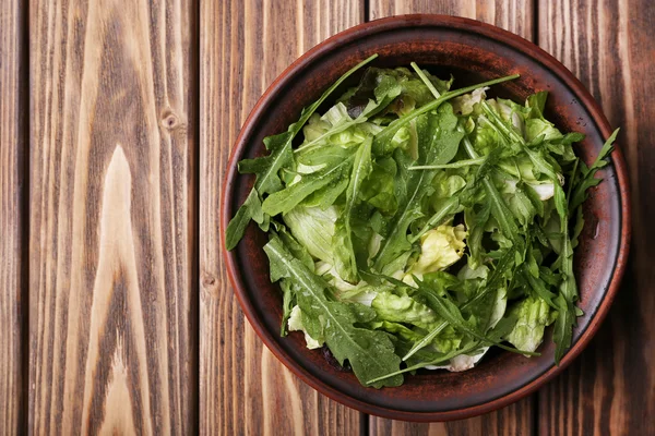 Kopfsalat mit Rucola in Schale auf Holzgrund — Stockfoto