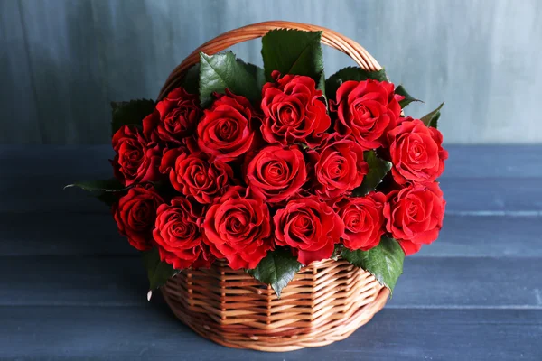 Μπουκέτο από κόκκινα τριαντάφυλλα σε καλάθι σε ξύλινα φόντο — Φωτογραφία Αρχείου