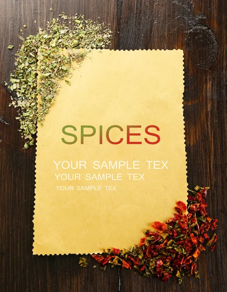 Spices on paper sheet on wooden background — Stock Photo, Image
