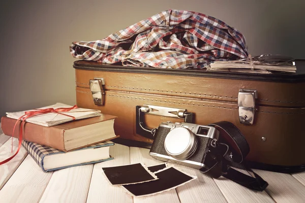 Rocznika walizki z ubrań i książek na stole na ciemnym tle — Zdjęcie stockowe