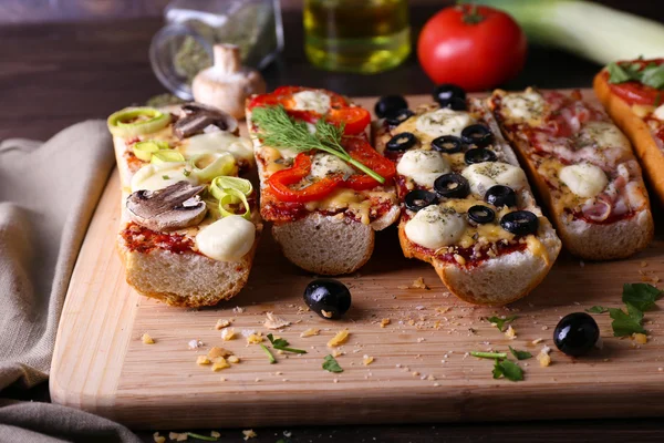Different sandwiches with vegetables and cheese on cutting board on table close up — Stock Photo, Image