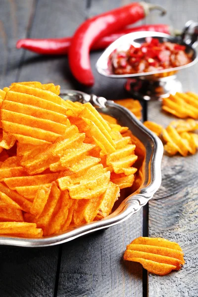 Delicious potato chips on plate on wooden table close-up — ストック写真