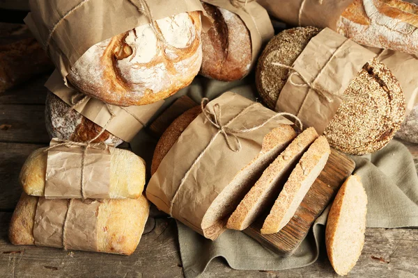 Different fresh bread, on old wooden table — Stock Photo, Image