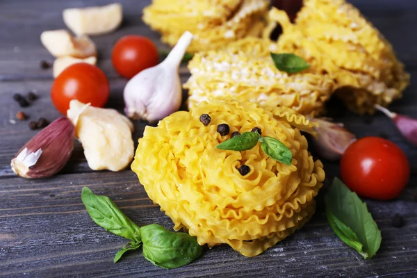 Raw pasta with cheese and vegetables on wooden background — Stock Photo, Image