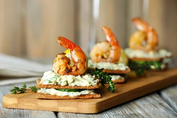 Appetizer canape with shrimp and cucumber on plate on table close up