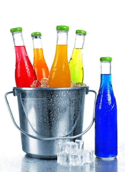 Bottles of tasty drink in metal bucket with ice isolated on white — Stock Photo, Image