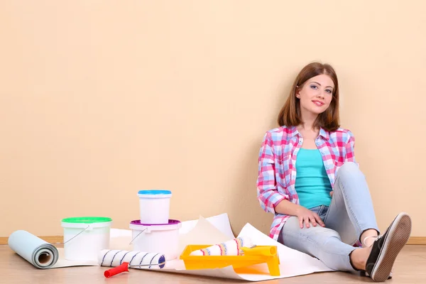 Beautiful girl sitting on floor with equipment for painting wall — Stock Photo, Image