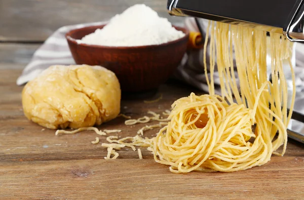 Hacer vermicelli con máquina de pasta sobre fondo de madera —  Fotos de Stock