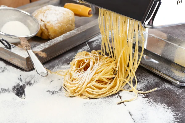 Hacer vermicelli con máquina de pasta y harina espolvoreada sobre fondo de madera —  Fotos de Stock