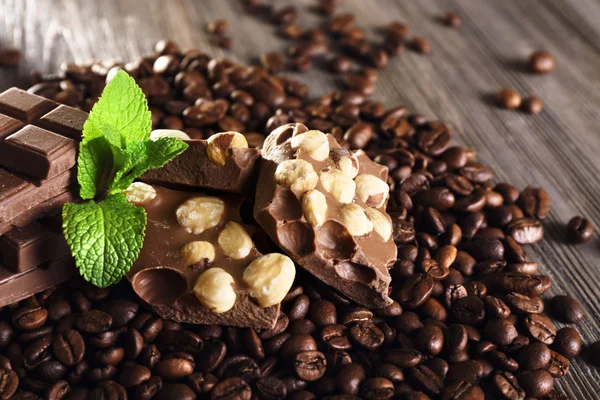 Chocolade met munt en koffie bonen op houten tafel, close-up — Stockfoto