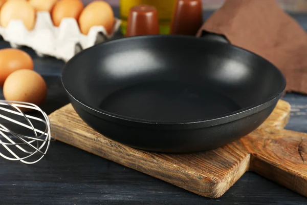 Still life with eggs and pan on wooden background — Stock Photo, Image