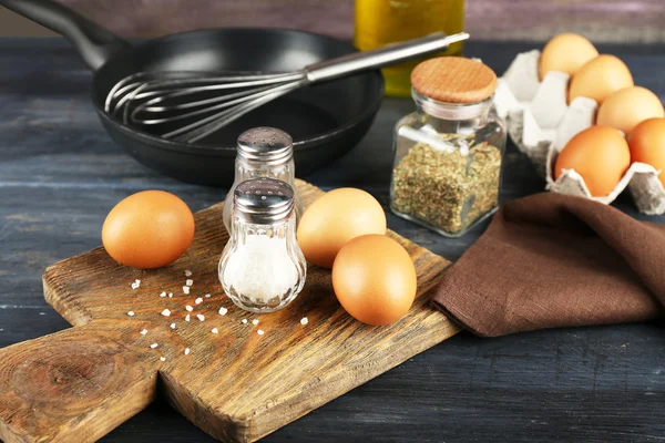 Stilleben med ägg och pan på trä bakgrund — Stockfoto