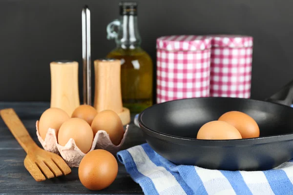 Stilleven met eieren en pan op houten achtergrond — Stockfoto