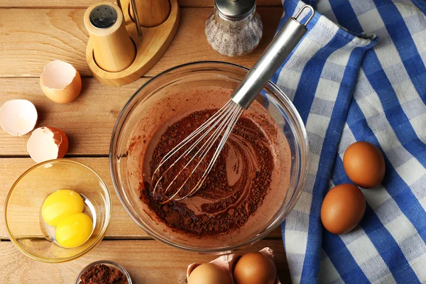 Preparation cream with eggs and cocoa in glass bowl on wooden background — Stock Photo, Image