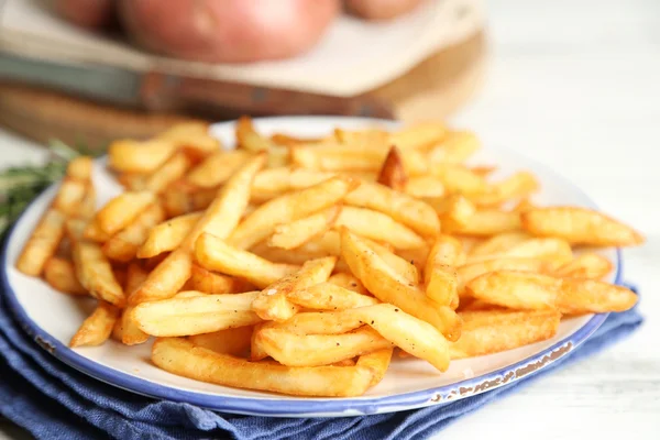 Sabrosas papas fritas en plato, sobre fondo de mesa de madera —  Fotos de Stock