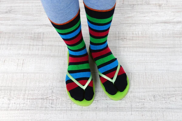 Pies femeninos en calcetines con chanclas rosadas, sobre fondo de piso — Foto de Stock