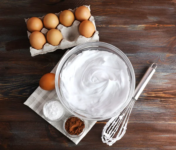 Brancos de ovo chicoteado e outros ingredientes para creme na mesa de madeira, vista superior — Fotografia de Stock