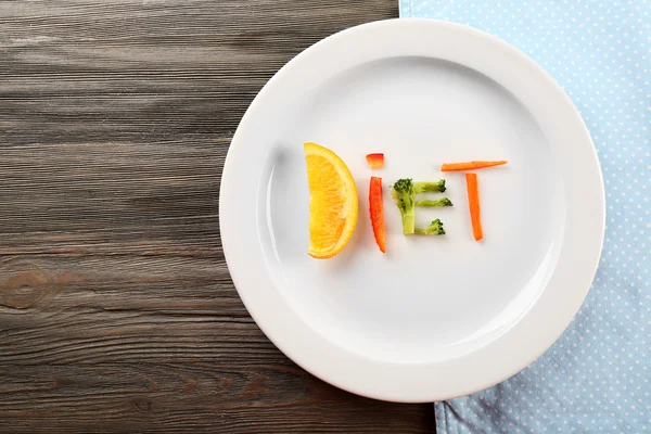 Word DIET made of sliced vegetables in plate on wooden table, top view — Stock Photo, Image