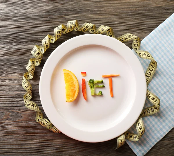 Слово DDT из скользящих овощей в тарелке с клейкой лентой на деревянном столе, вид сверху — стоковое фото