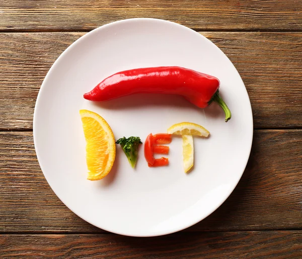 Słowo dieta wykonane w plasterkach warzywa w białe płytki na drewnianym stole, widok z góry — Zdjęcie stockowe