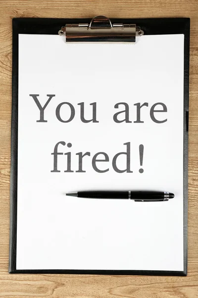 Message You're Fired on clipboard on wooden table, closeup — Stock Photo, Image